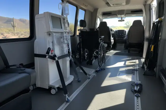 Interior of a transport van with secure floor tracks and straps in Mesa, AZ, with the desert view outside.