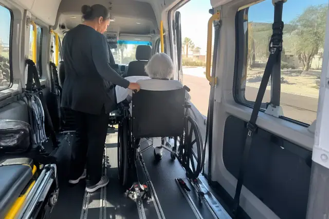 Hospital discharge transportation van interior in Gilbert, AZ, showing padded walls, secure floor tracks, and desert glare.