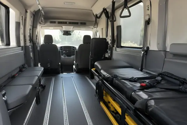 Long-distance medical transport van interior in Gilbert, AZ with padded walls, floor tracks, and grab handles.
