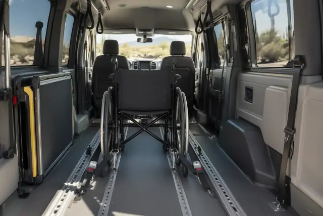 Padded transport van interior with secure floor tracks and folded mobility ramp in Sun Lakes, AZ.