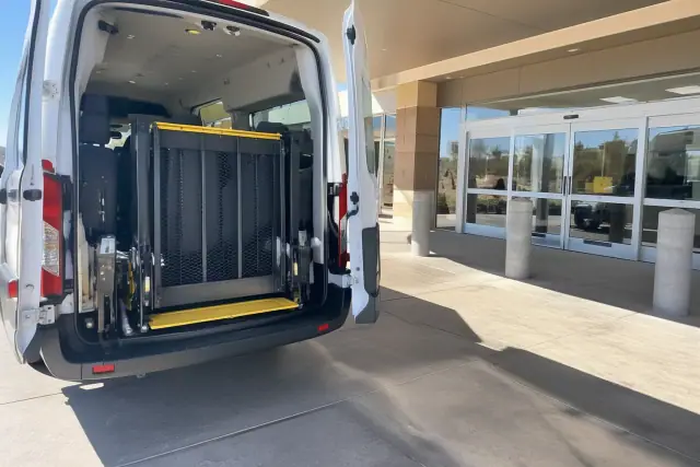 Medical transport vehicle with a secured wheelchair lift at a hospital loading bay in Tempe, AZ.