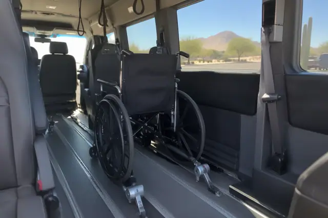 Wheelchair restraint clamp locked to a floor track inside a medical transport van in Gold Canyon, AZ.