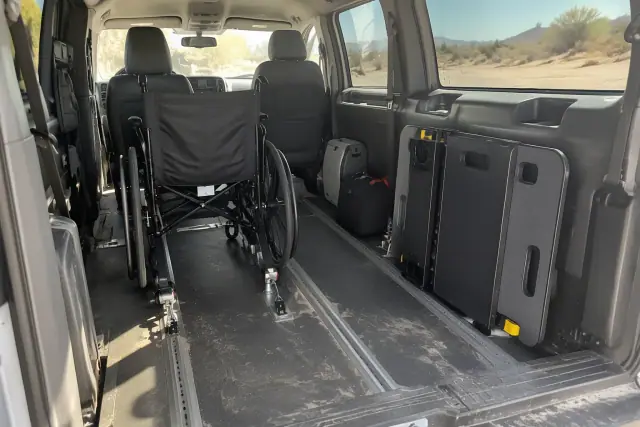 Transport van interior in Mesa, AZ, showing secure floor tracks, a folded wheelchair, and transfer boards.