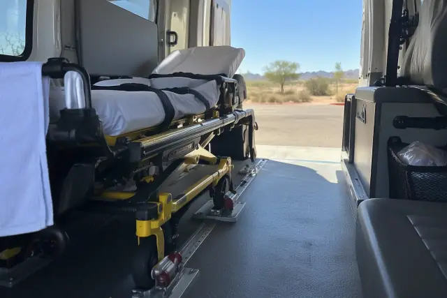 Medical transport stretcher secured to floor lock brackets inside a van in Gilbert, AZ.
