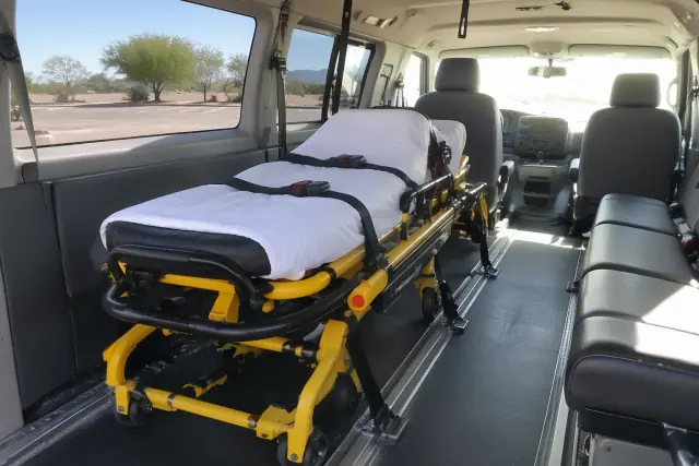 Stretcher secured with floor tracks and straps inside a medical transport van in Chandler, AZ.