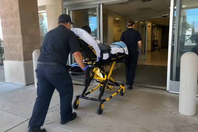 Two transport attendants loading a stretcher into an ambulance bay in Mesa, AZ.