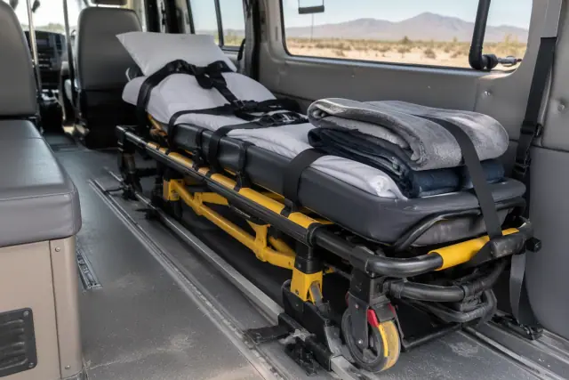 Medical transport stretcher secured in a vehicle in Mesa, AZ, with fleece blankets and safety straps.