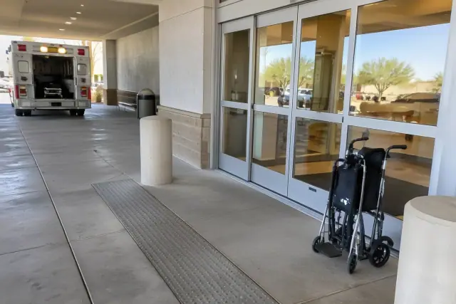Folded transport chair near hospital discharge sliding doors in Mesa, AZ.