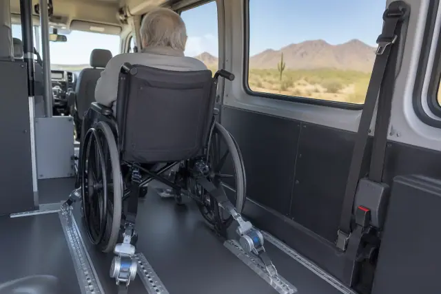 Interior of a transport van in Mesa, AZ, showing a locked mobility device secured on floor tracks.