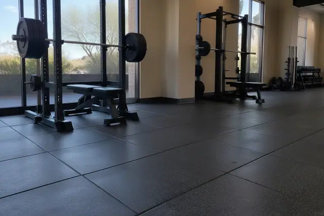Commercial rubber gym flooring installed beneath barbell racks in a Mesa, AZ gym facility.