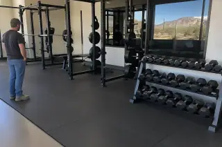 Thick rubber flooring installed under heavy barbell racks and dumbbell stations in Mesa, AZ.