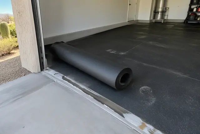 Rolled rubber garage flooring installed in Mesa, AZ, showing edge seams and adhesive residue.