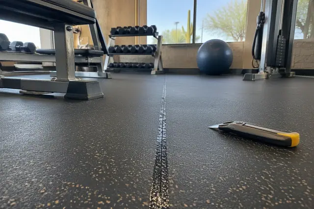 Repaired rubber gym flooring seam with a utility knife at a commercial facility in Mesa, AZ.