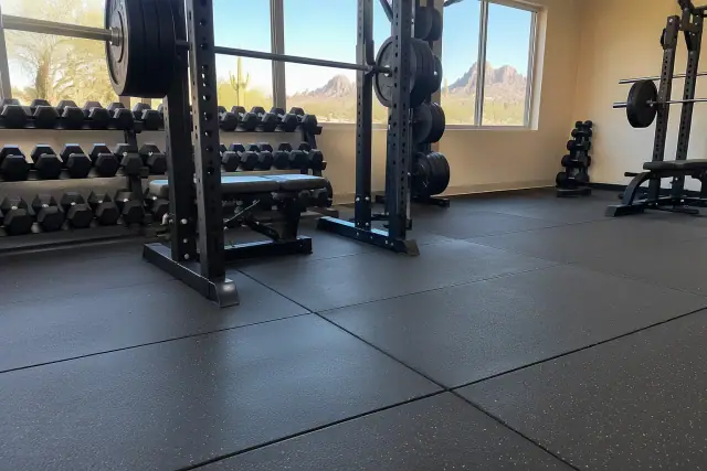 Dense interlocking rubber flooring installed beneath heavy weight racks in Apache Junction, AZ.