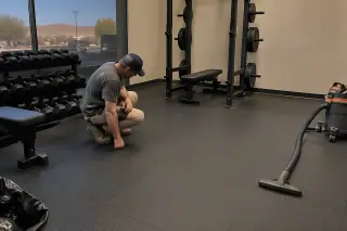 Worker checking clean rubber flooring and barbell racks during a final inspection in Mesa, AZ.