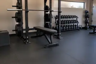 Thick rubber flooring installed beneath heavy barbell racks in Mesa, AZ.