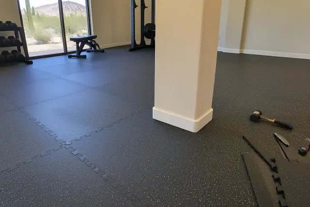 Rubber gym flooring installation progress around a corner column in a Mesa, AZ residential basement.