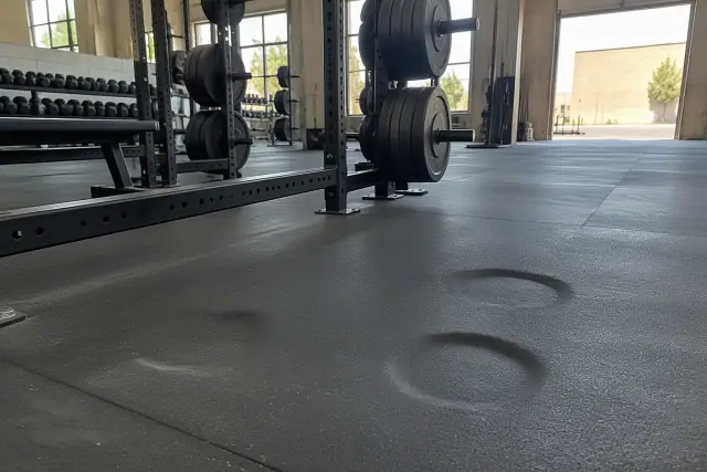 Permanent dents and weight-plate impressions on thick rubber flooring in a Mesa, AZ gym.