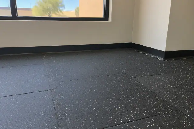 Rubber floor tile installation in progress in Gilbert, AZ, showing seamless interlocking tiles along a baseboard.