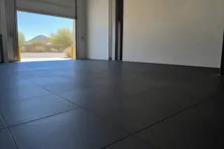 Thick rubber floor tiles installed near a warehouse roll-up door and stucco wall in Mesa, AZ.