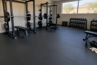 Wide view of thick rubber flooring installed under barbell racks in Mesa, AZ.
