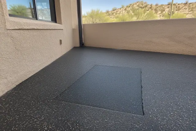 Fresh rubber patch in a commercial floor repair in Mesa, AZ, near a stucco wall.