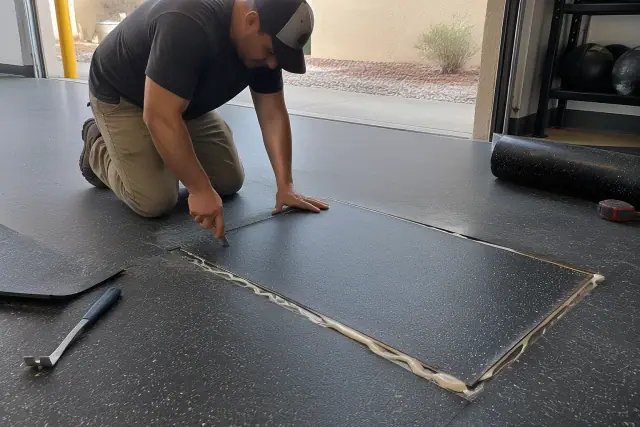 Technician repairing damaged rubber flooring with a freshly bonded patch seam in San Tan Valley, AZ.