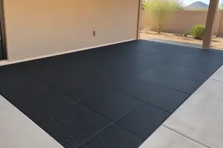 Thick impact-absorbing rubber flooring set against a stucco exterior wall in Mesa, AZ.