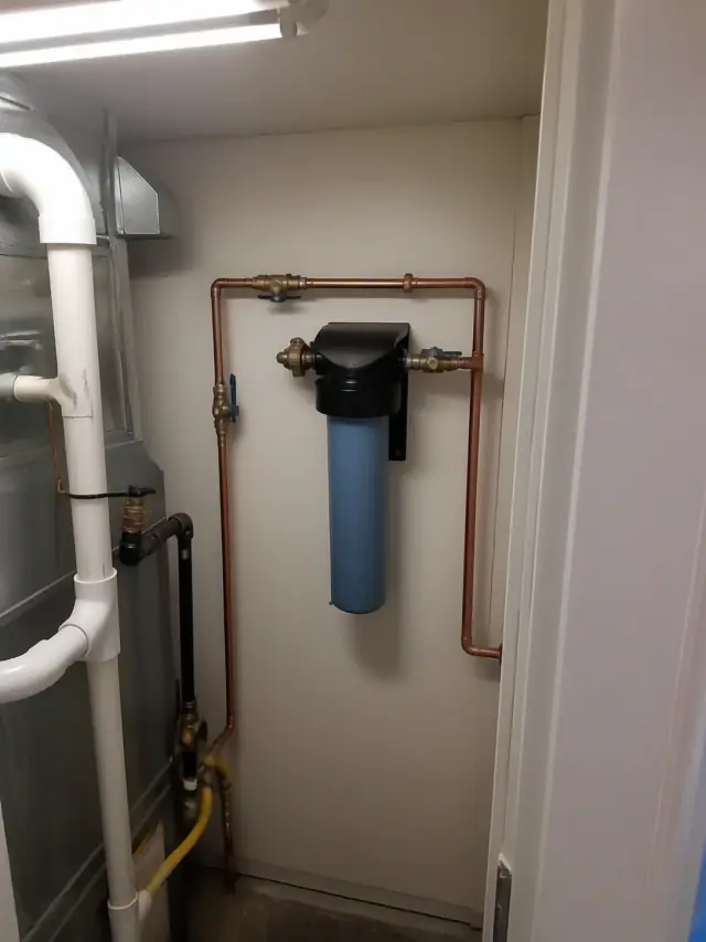 Saltless water softener installed on a wall with copper pipes in a mechanical room in Chandler, AZ.