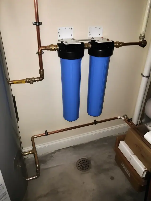 Whole-house water filtration system with copper piping installed in a residential utility room in Mesa, AZ.