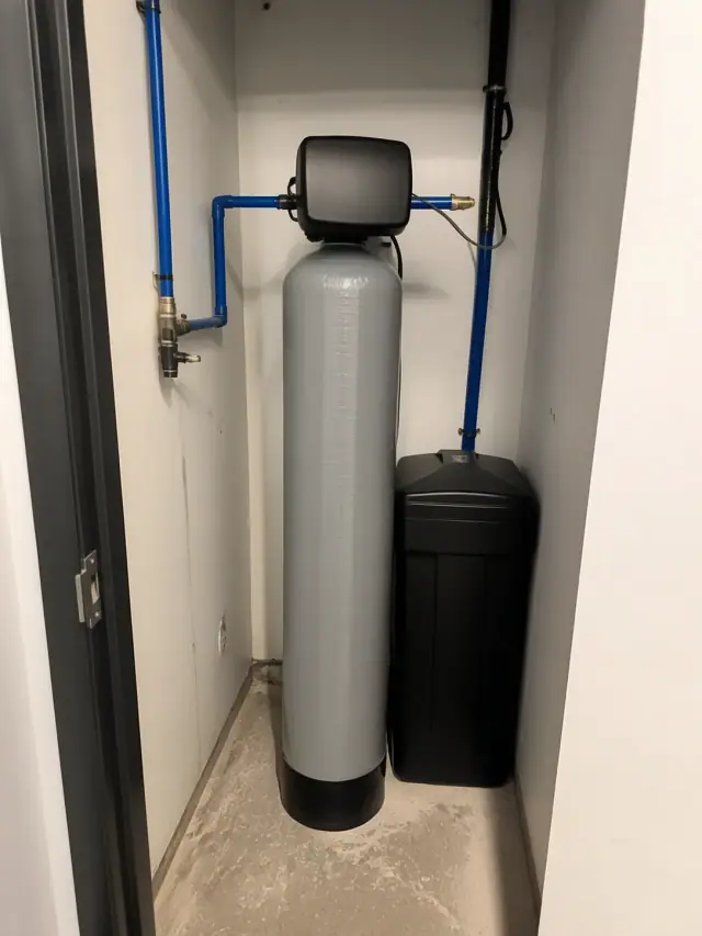 Salt water softener installation with blue PEX piping in a small utility closet in Tempe, AZ.