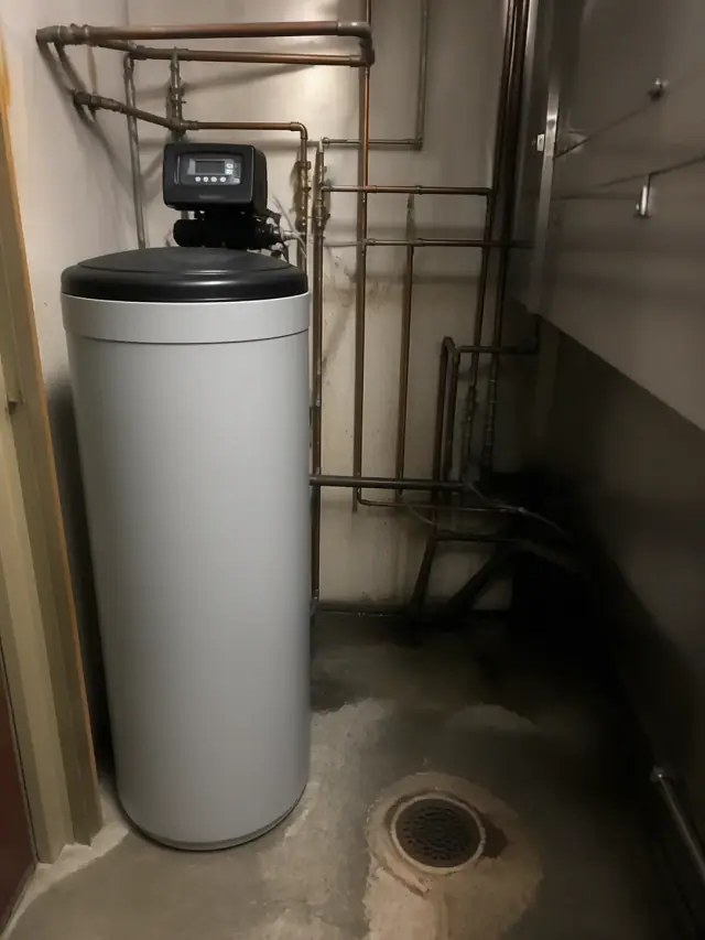Industrial water softener system repair with copper piping in a dimly lit back room in Tempe, AZ.