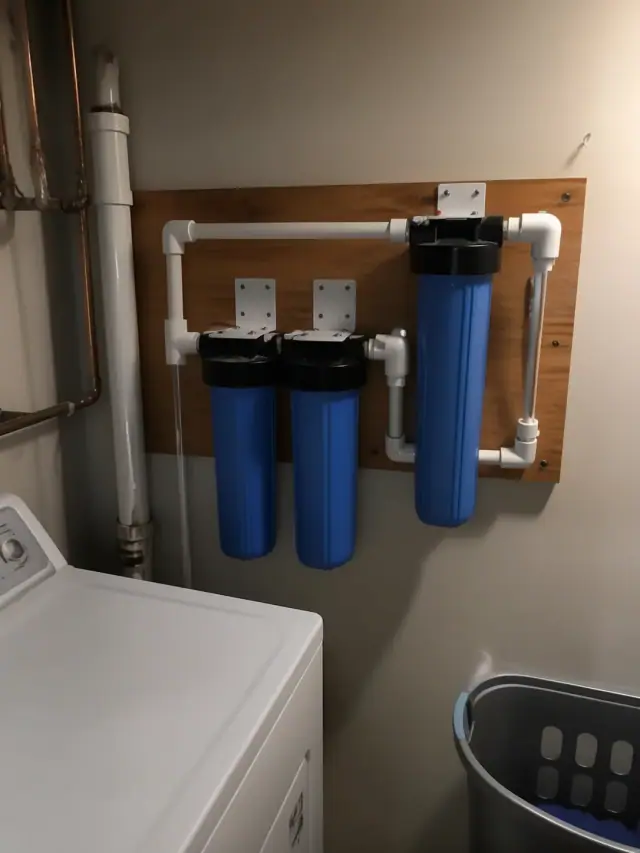 Completed water filtration system with blue filter housings installed in a laundry room in Mesa, AZ.