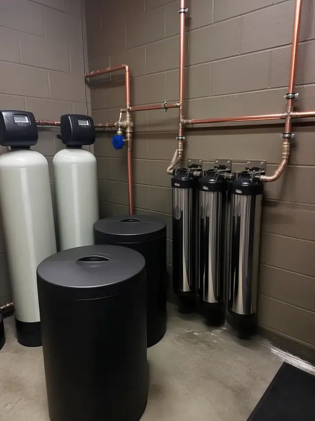 Commercial water softener system with stainless steel filters and copper pipes in a Chandler, AZ retail store.