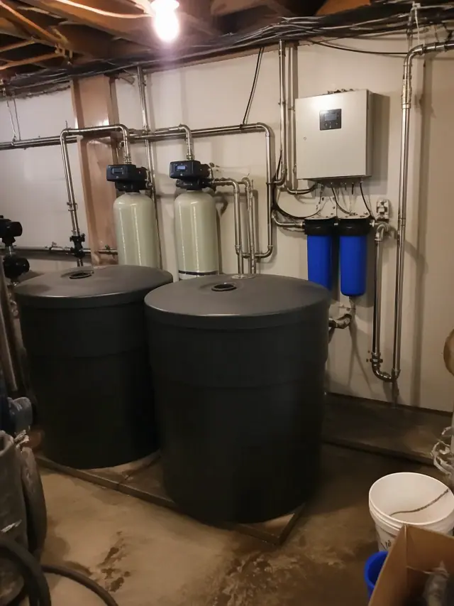 Commercial water softener system with stainless steel pipes and brine tanks installed in a mechanical room in Mesa, AZ.