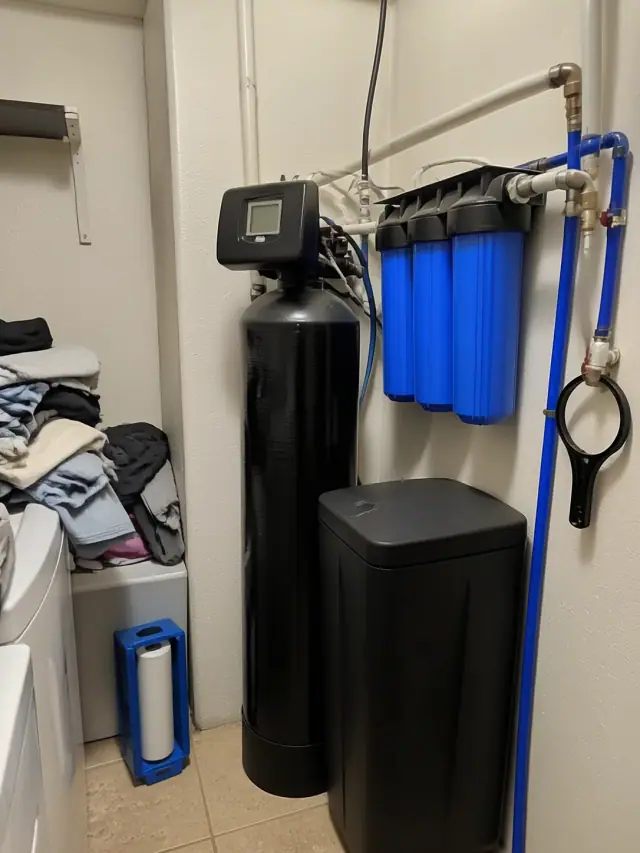 Whole house water filtration system with a softener tank and blue prefilter in a laundry room in Phoenix, AZ.
