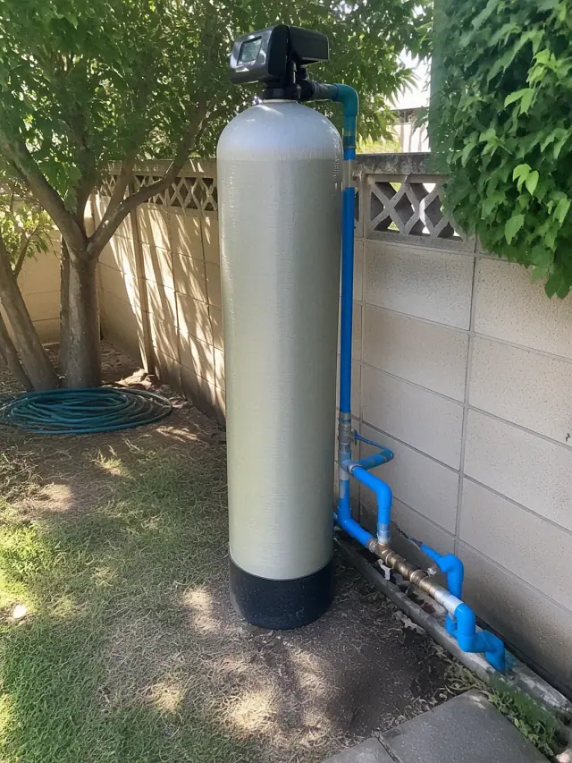 A fiberglass water filtration tank with blue plumbing and brass fittings installed in a residential backyard in Mesa, AZ.