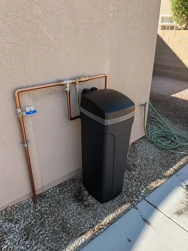 Newly installed saltless water softener connected to exterior plumbing at a home in Mesa, AZ.