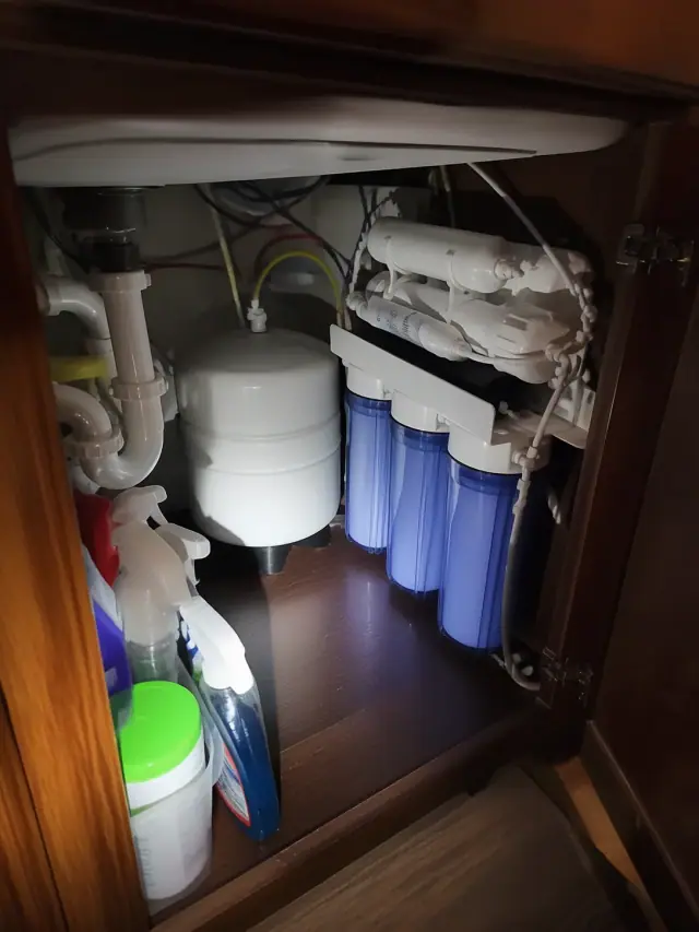Reverse osmosis system with white tanks and blue filters installed under a kitchen sink in Mesa, AZ.
