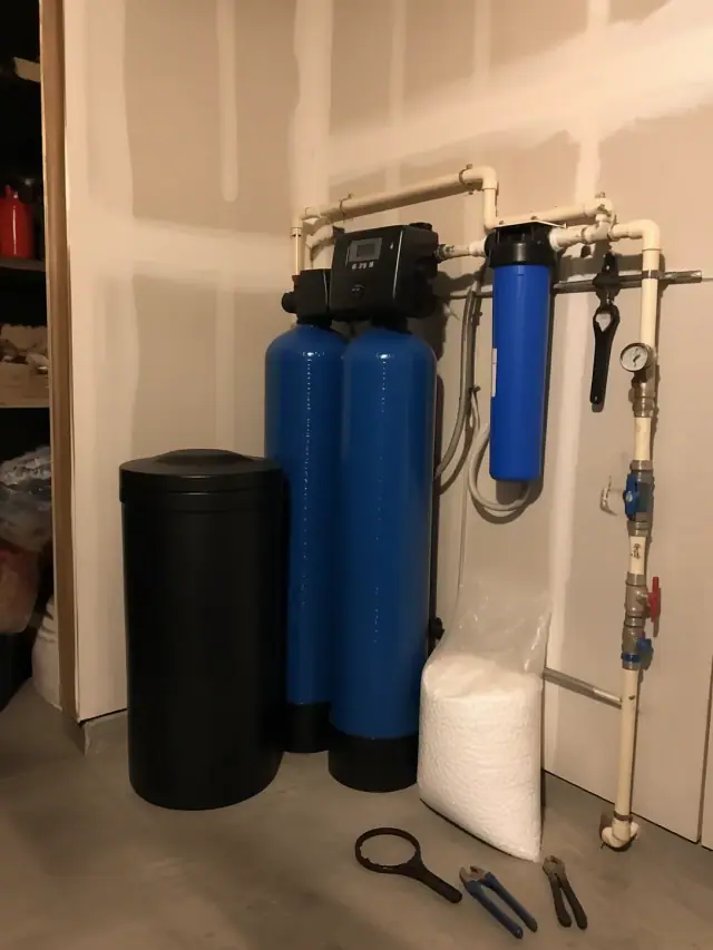 Well water treatment system with two blue tanks and pipes installed in a garage in Mesa, AZ.
