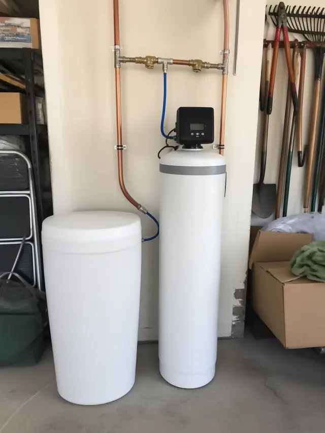 Newly installed water softener system with white tanks and copper piping in a garage in Peoria, AZ.