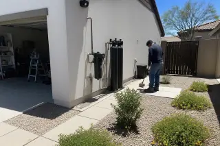 Technician cleaning up a carbon filtration system installed beside a house and garage in Mesa, AZ.