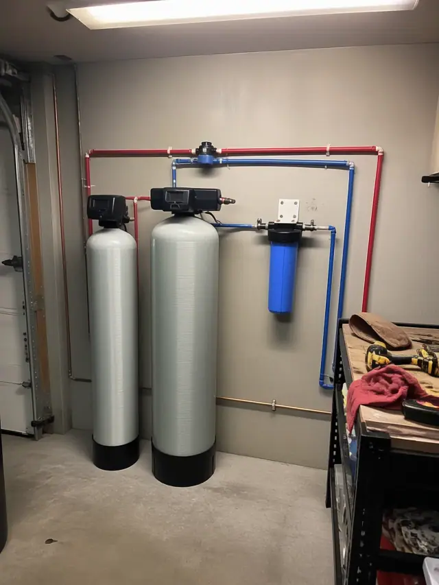 Whole-house water filtration system with tanks and blue filter housing installed in a garage in Mesa, AZ.