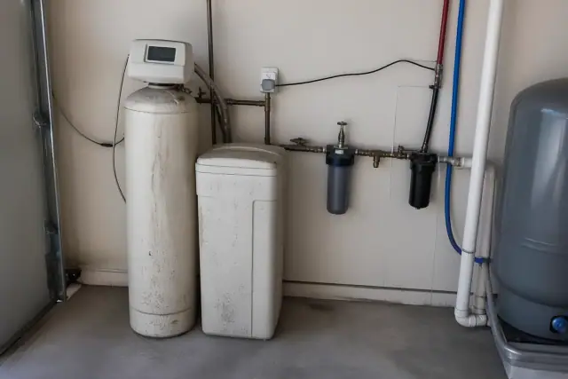 Water softener unit and plumbing pipes in a residential garage in Mesa, AZ.