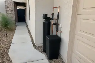 Water softener system with copper piping and insulated fittings against a stucco wall in Mesa, AZ.