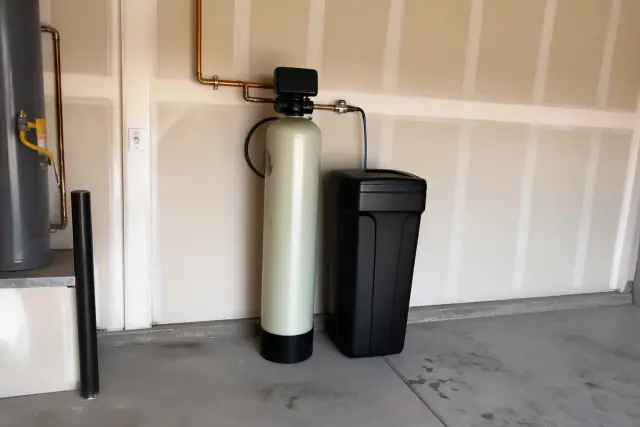 A serviced water softener system with a resin tank and control valve in a residential garage in Mesa, AZ.