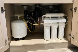 Reverse osmosis system with organized tubing and white filtration housing installed under a sink in Mesa, AZ.
