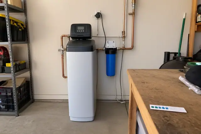 Water softener unit installed on a residential garage wall in Mesa, AZ.
