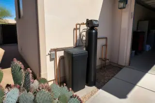 Water softener installation with neatly plumbed pipes beside a desert landscape in Mesa, AZ.