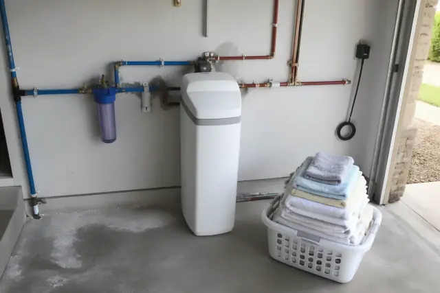 Water softener unit installed on a residential garage wall in Mesa, AZ, with neatly connected PEX piping.